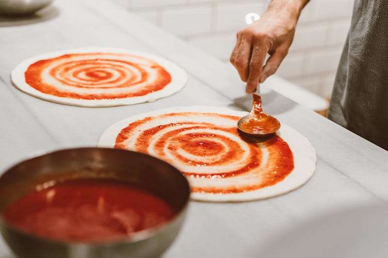 Fresh pizza dough being hand-stretched in the kitchen